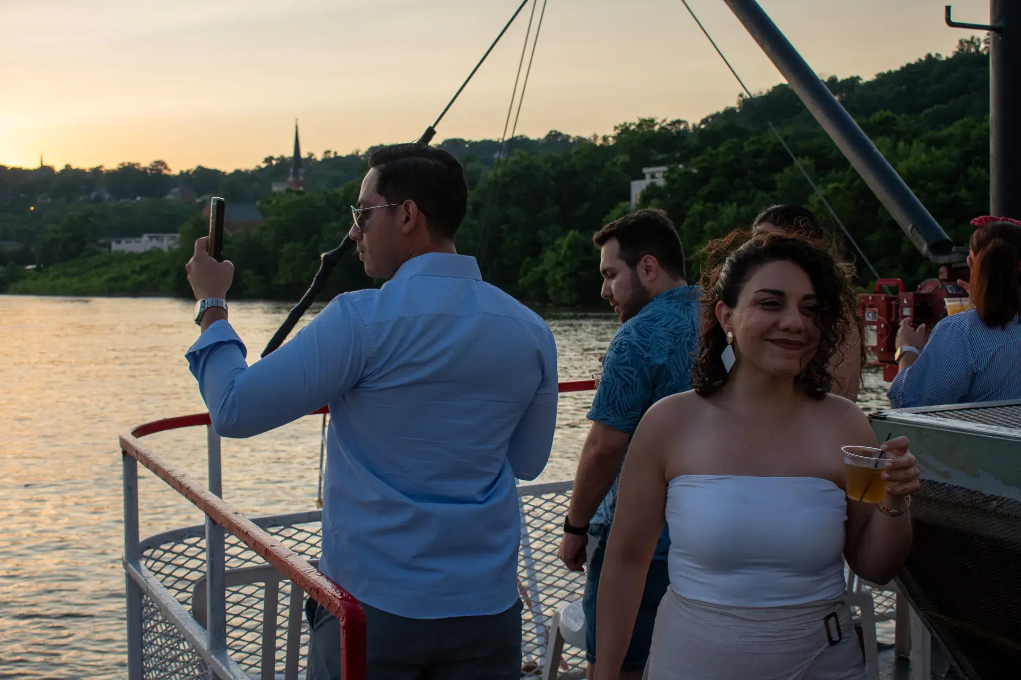 Guests on the open-air deck of a riverboat at golden hour on the Ohio River