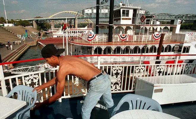 A crew member setting out tables and chairs on a riverboat deck at the Cincinnati Public Landing before a cruise
