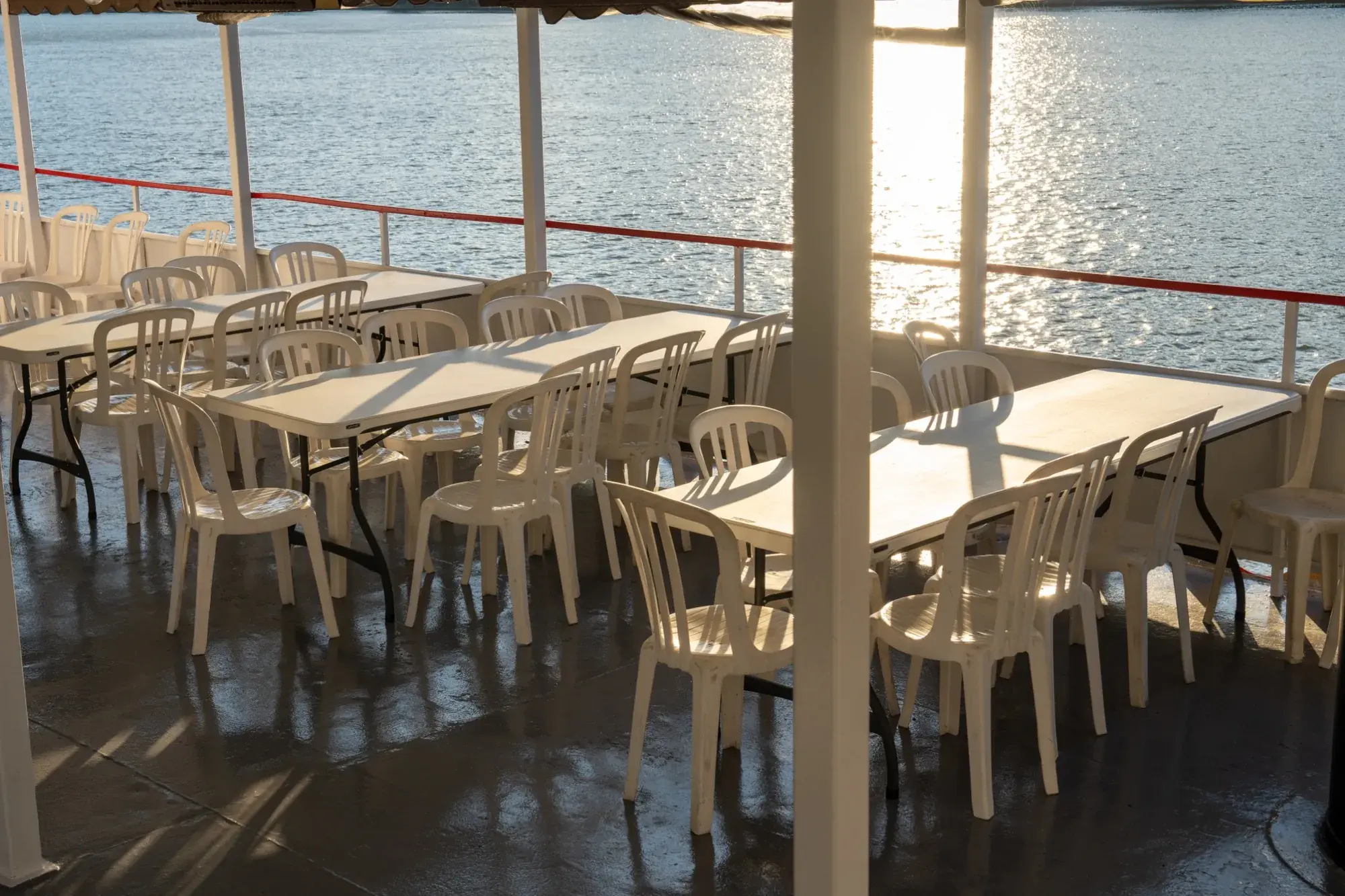 The open-air top deck set with tables and chairs for dining on the Ohio River